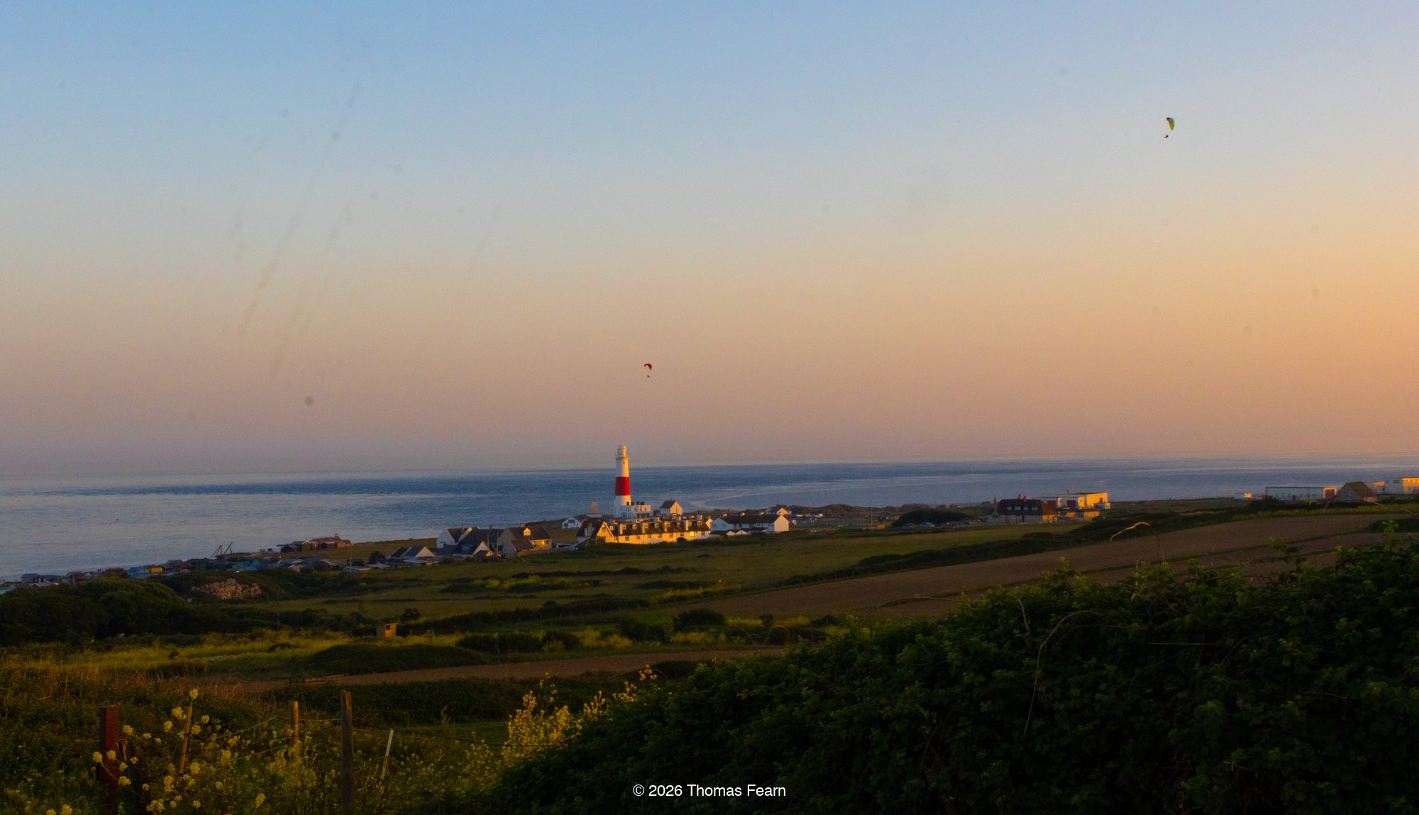 Paragliders on the coastline at sunset